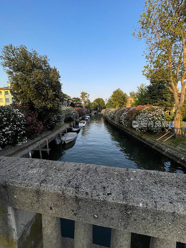 从意大利威尼斯丽都威尼斯四喷泉桥(Ponte delle Quattro Fontane)上的运河景观特写，风化的铸石栏杆，色彩缤纷的建筑，系泊的船只，湛蓝晴朗的天空，逐渐缩小的视角